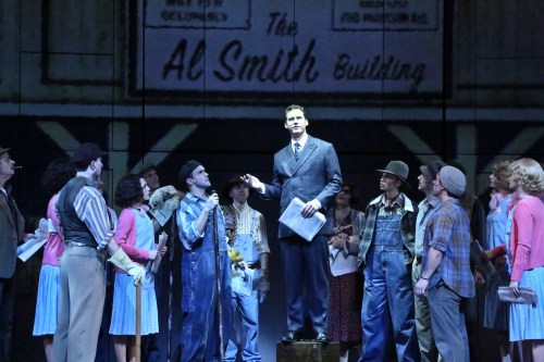Kevin Earley as “Michael” is determined to “Do What We Need To Do” to get the building finished as the company cheers him on.