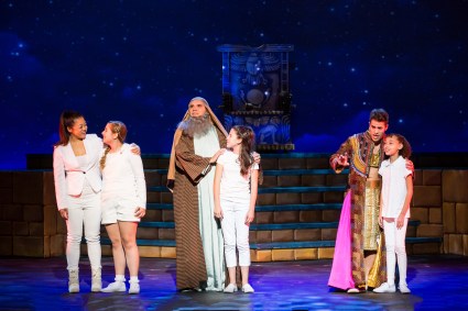 “May I return to the beginning, the light is dimming and the dream is too; the world and I, we are still waiting, still hesitating…Any Dream Will Do.” Charlotte Mary Wen as “The Narrator”, Bryan Dobson as “Jacob” and Justin Anthony Long as “Joseph” are joined by several younger members of the cast of 3-D Theatrical’s “Joseph & The Amazing Technicolor Dreamcoat”