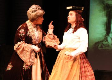 “Could you practice self-control? Could you possibly be ‘shy’? Could you wear a corset tight in the heat of mid-July?! These are rules you must obey—every one which you defy!” Sherry Domerego as “Aunt March” scolds Ashley Arlene Nelson as her Great-niece “Jo” about her ‘Un-Lady Like” behaviors in The Chance Theater’s “Little Women—The Musical” 